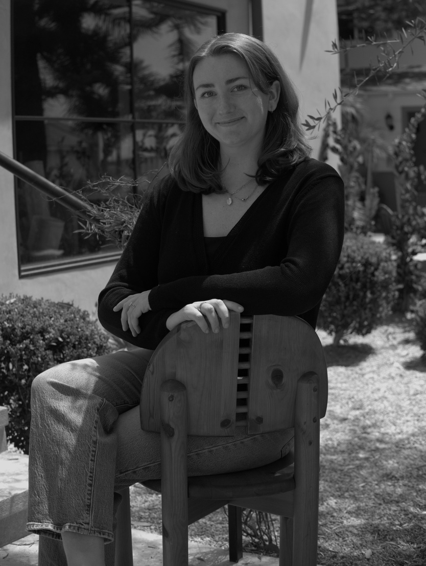 Portrait of the founder of Noxon Creative House seated on a wooden chair outdoors