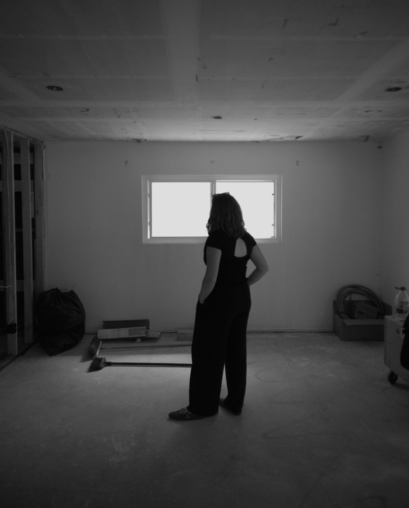 Interior of a home under renovation with light through a tall window